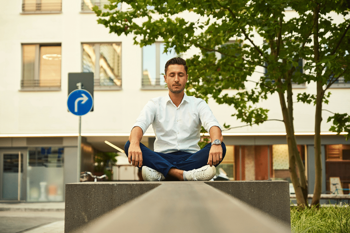 A man meditating on a city street - image to promote the idea of the power of meditation for business owners